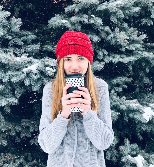 This is an image of me last year after a big snow storm. I am wearing a red winter hat and holding a mug. 