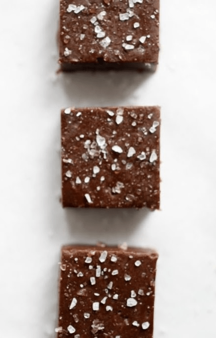 3 pieces of nutella fudge cut into squares and sprinkled with salt all lying on a white counter.